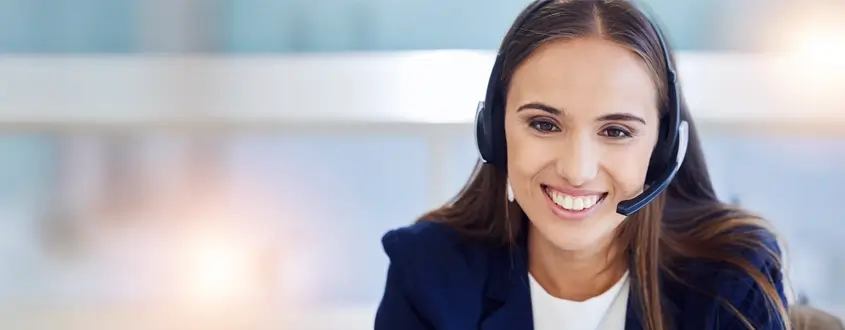 BlueChip Energy & Climate Solutions - Contact page image of a young woman smiling wearing a head set and microphone to answer phone calls.